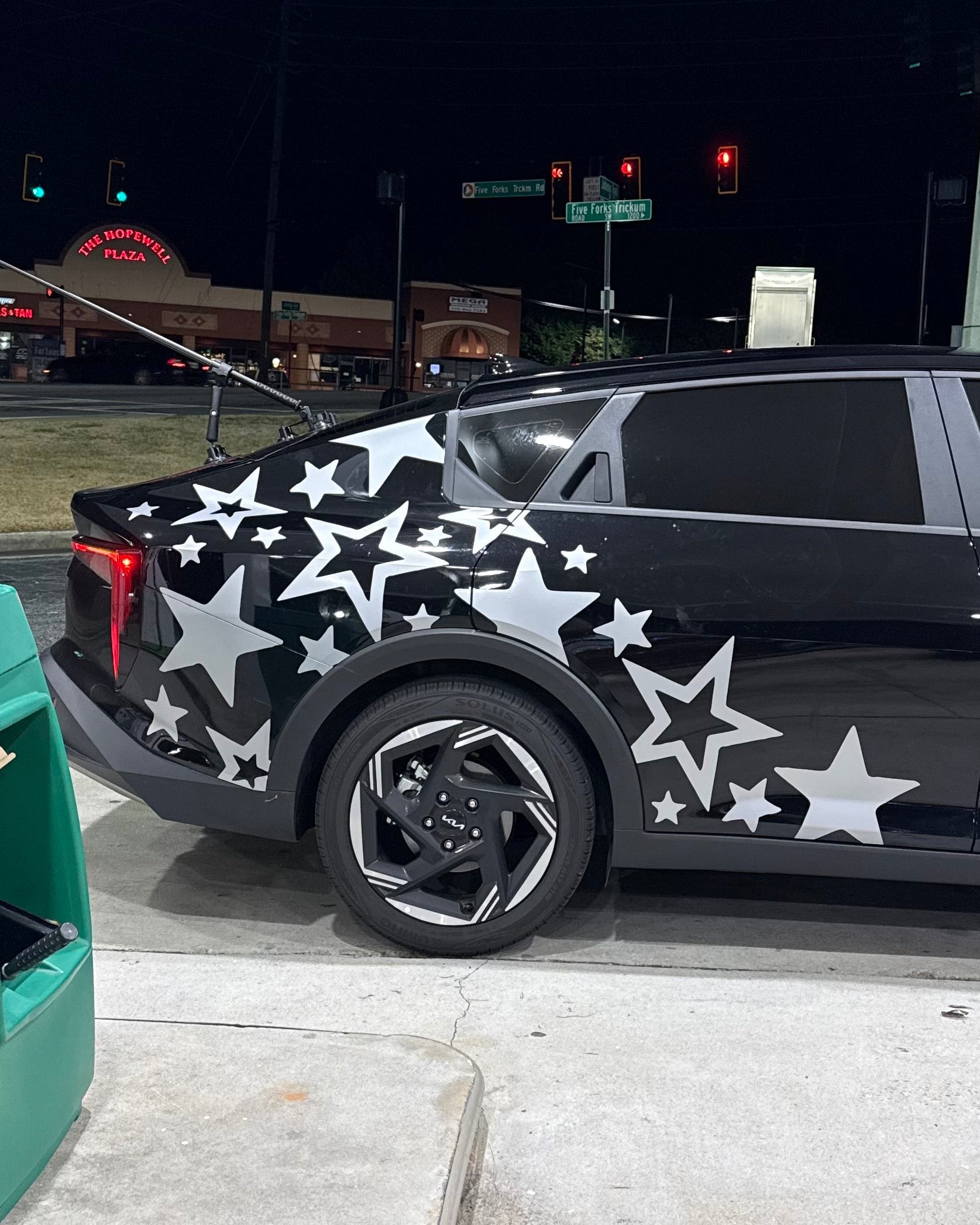 Black car with star patterns parked on a street at night