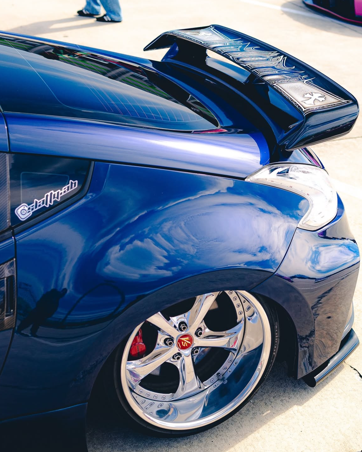 Blue car with custom rims on a pavement