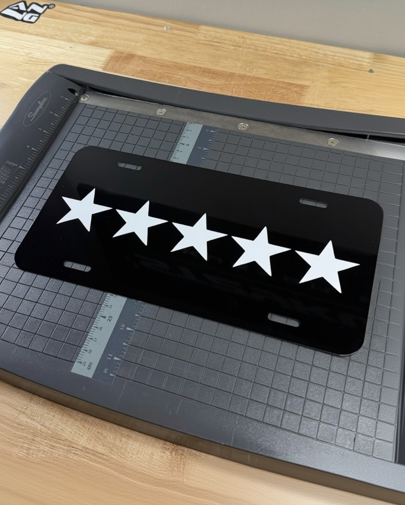 Black license plate with white stars on a cutting mat, with 'chellybxbb' branding.